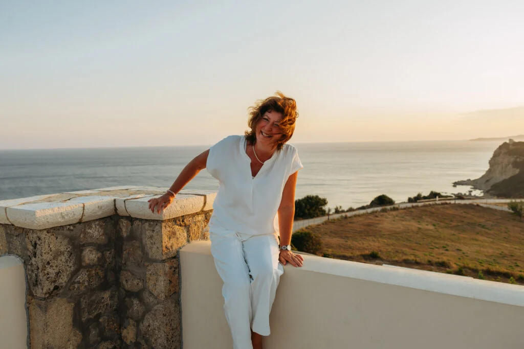 Olga Westerveld an einer Holzbank am Meer, Blick in die Kamera