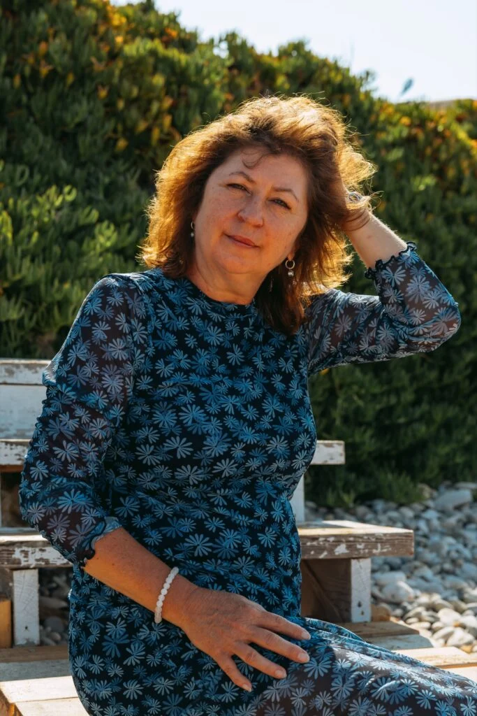 Olga Westerveld sitzt lächelnd auf einer Holzbank